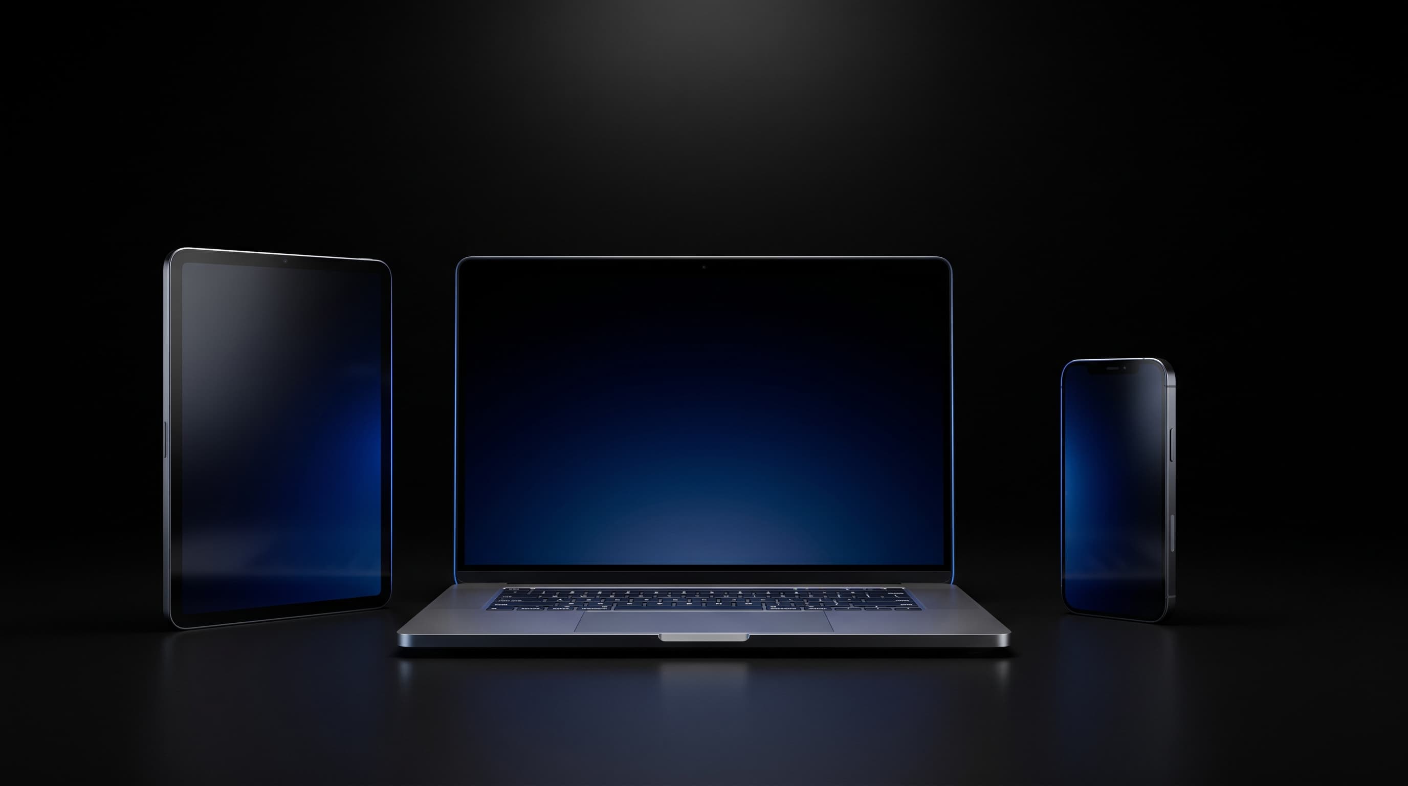 A laptop, a tablet and a smartphone with softly glowing blue screens on a black surface